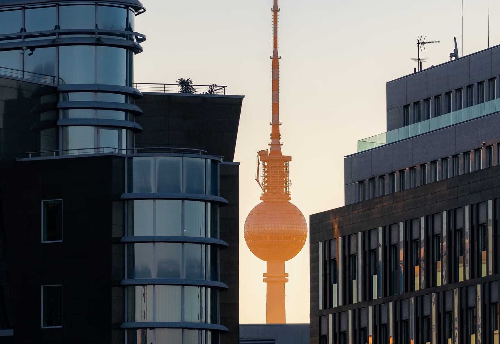 Berliner Fernsehturm zwischen modernen Bürofassaden vor hellem Himmel