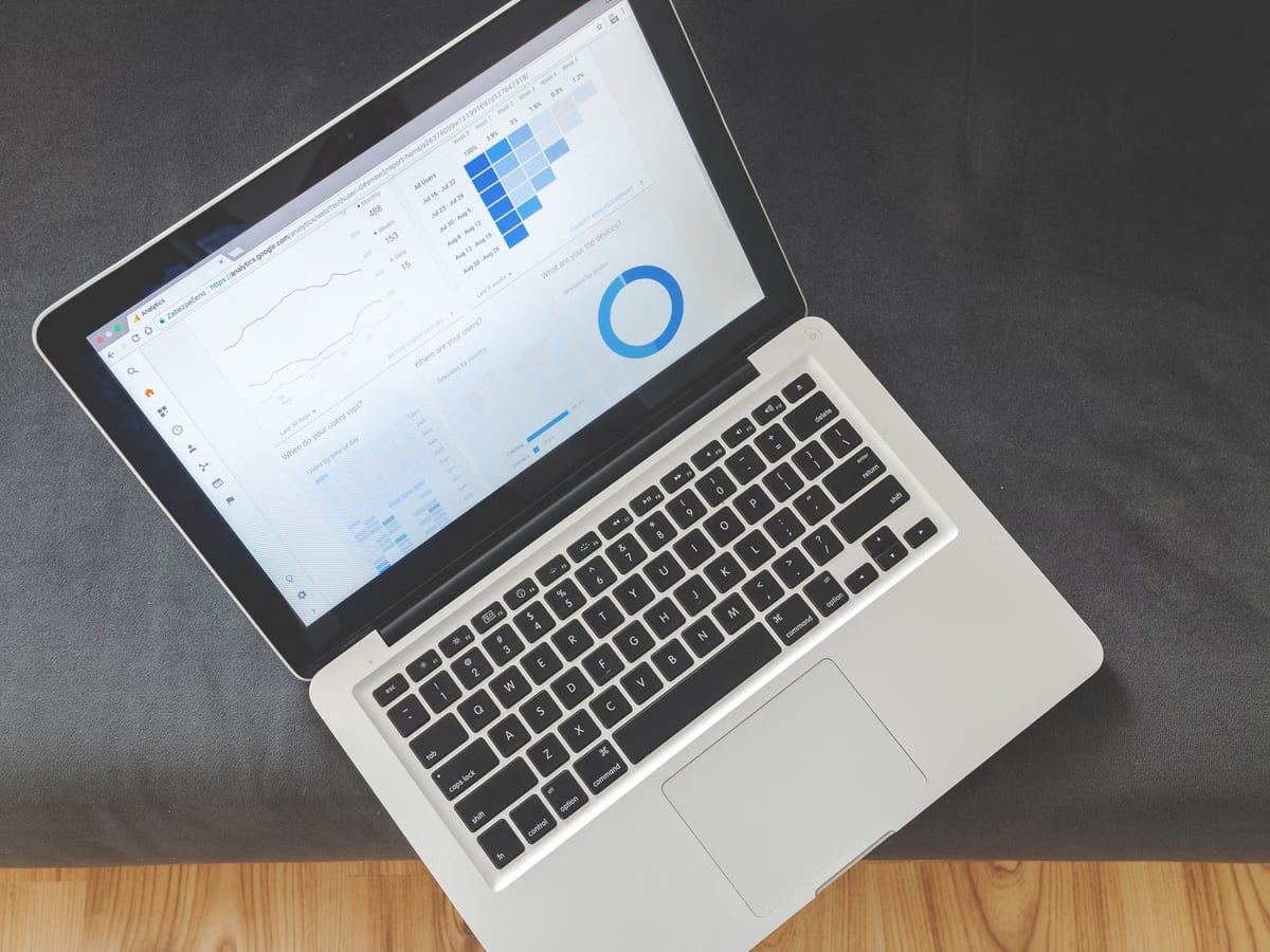 Von oben fotografierter Laptop auf grauer Fläche, auf dem Bildschirm ein Auswertungsbericht mit Diagrammen